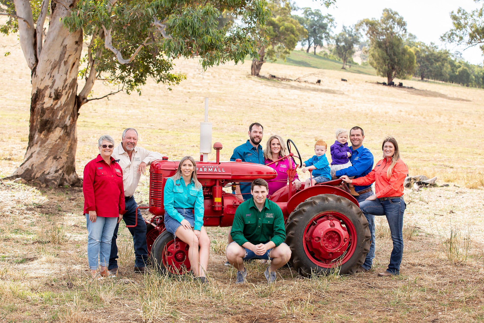 Family posing with a red tractor in a rural setting