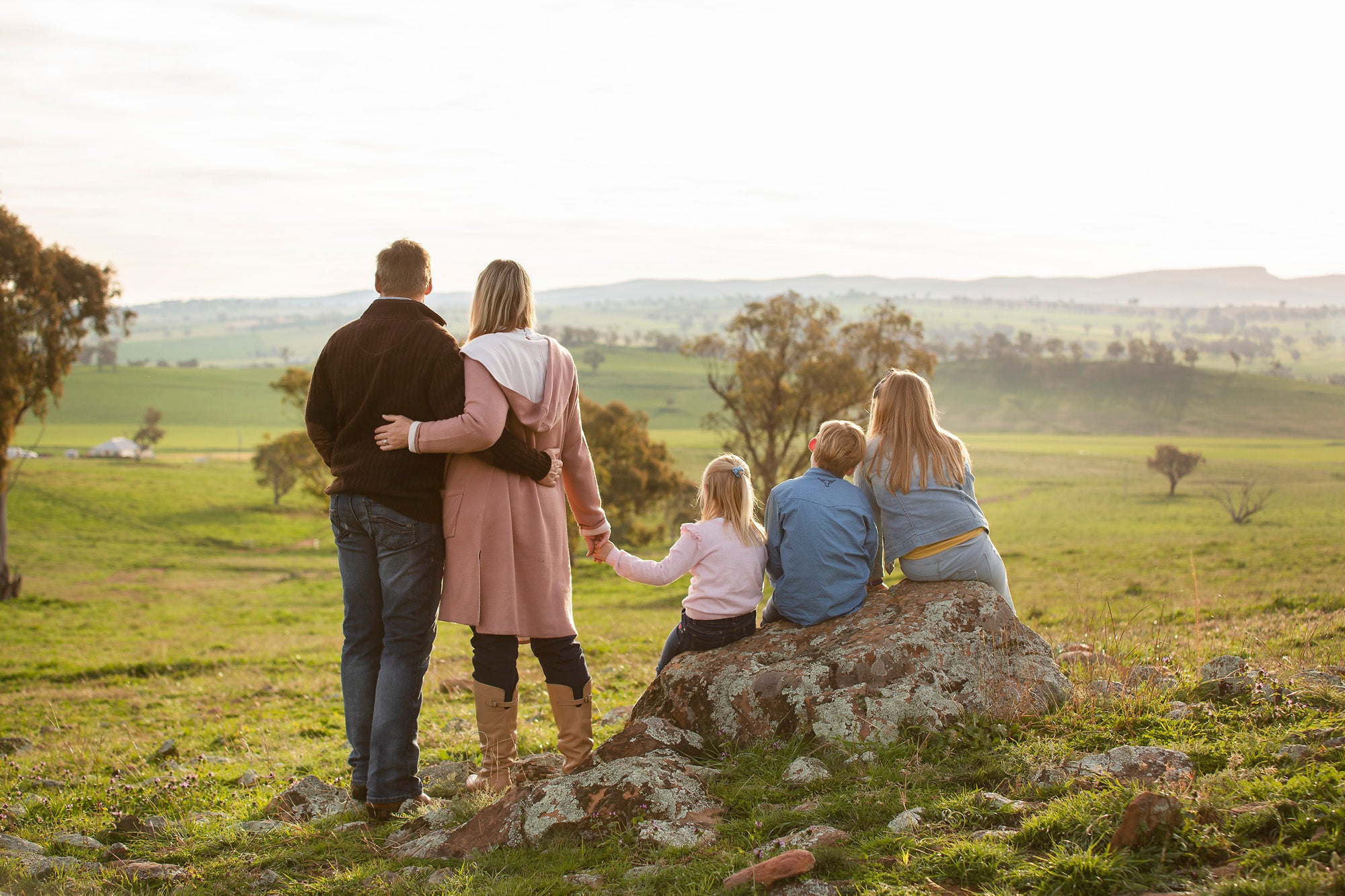 Family of five sitting on a rock overlooking a scenic landscape